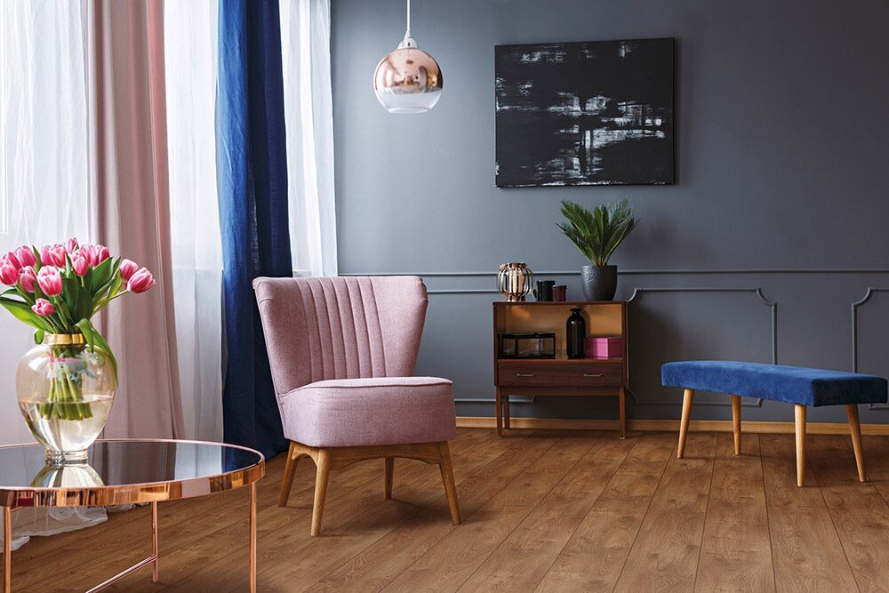Real photo of a pink armchair standing on a rug and under a lamp